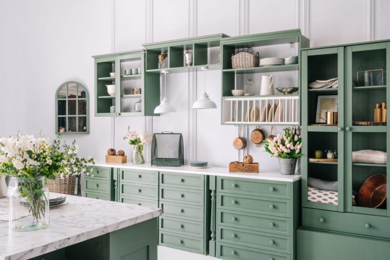 Big white kitchen with green furniture.